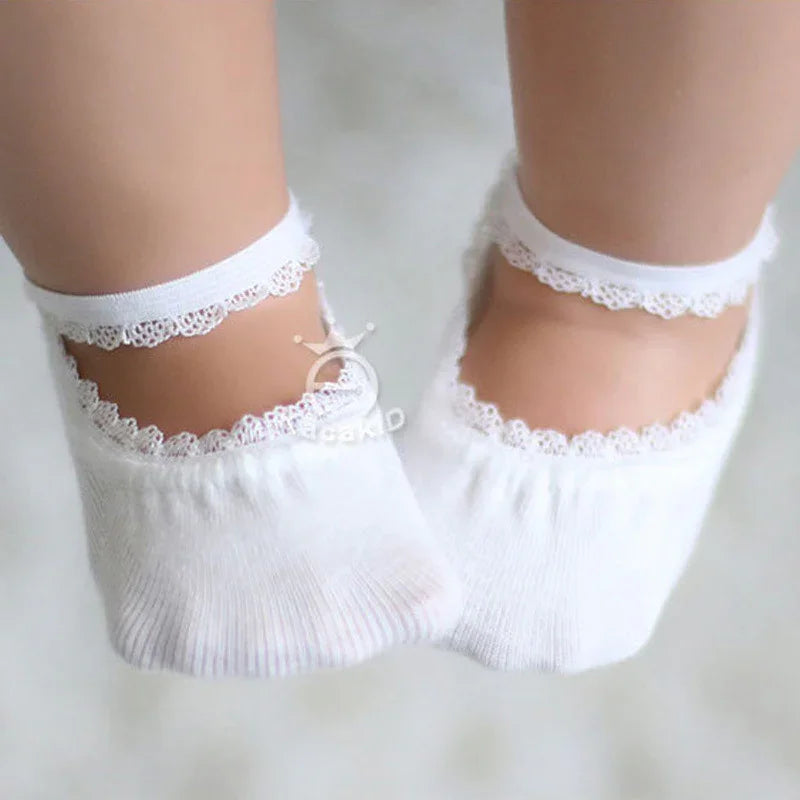 Close-up of feet wearing white ankle socks with lace trim on a light background