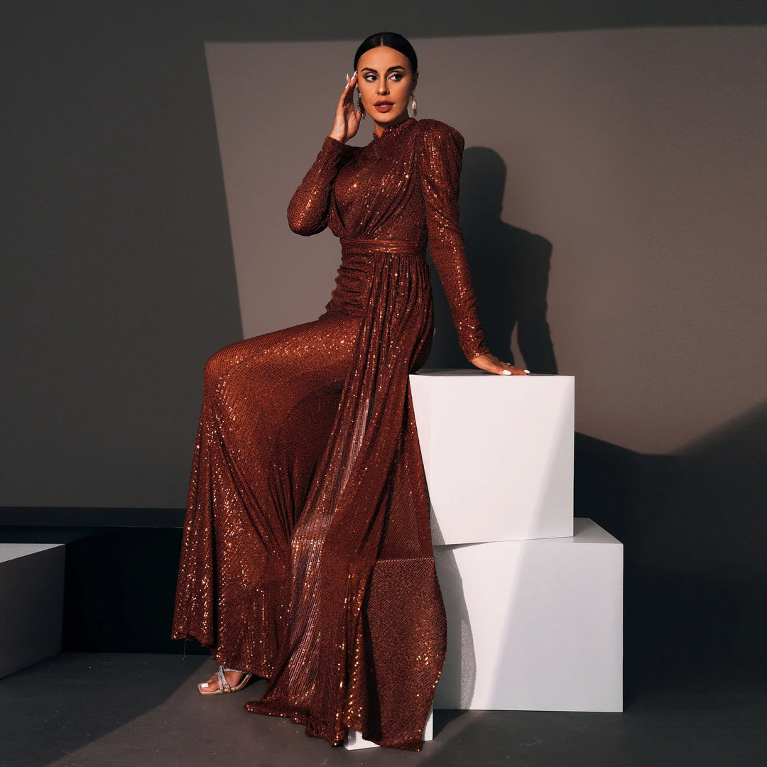 Woman in a shimmering rust-colored sequin evening gown posing beside white cubes in a studio setting