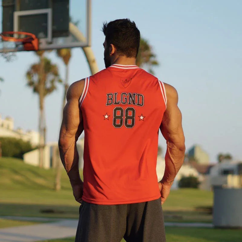 Muscular man in red sleeveless basketball jersey with BLGND 88 on back, standing by outdoor court