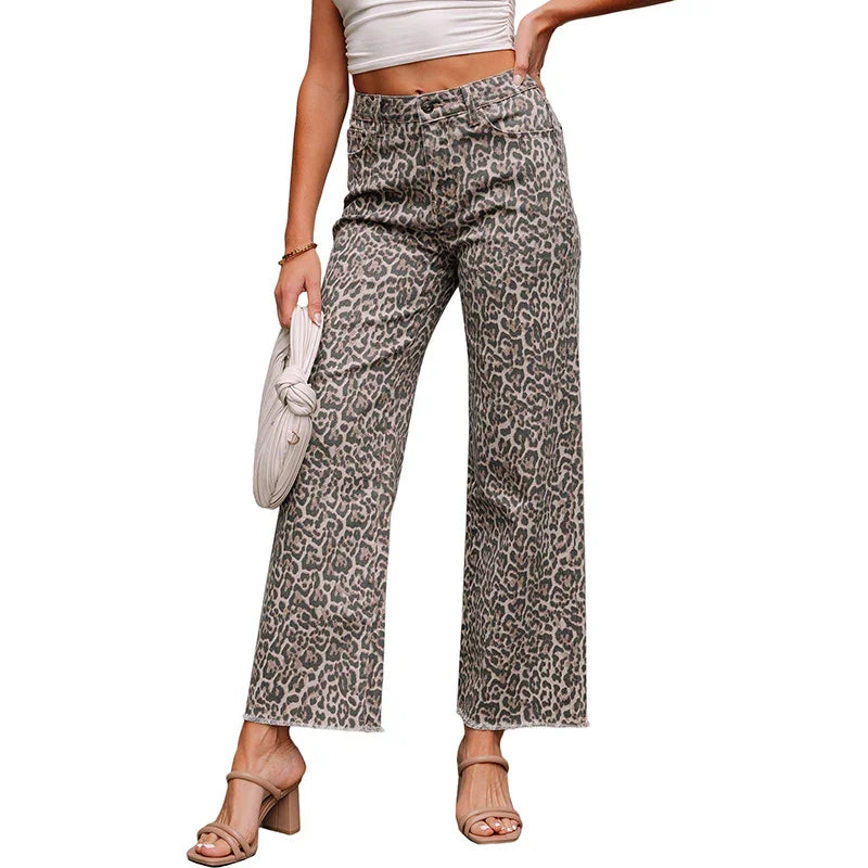 Woman wearing leopard print wide-leg pants with beige heeled sandals and holding a white clutch bag