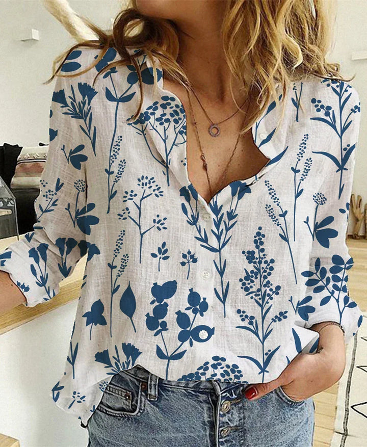 Woman wearing casual white blouse with blue botanical prints and rolled sleeves, paired with blue jeans