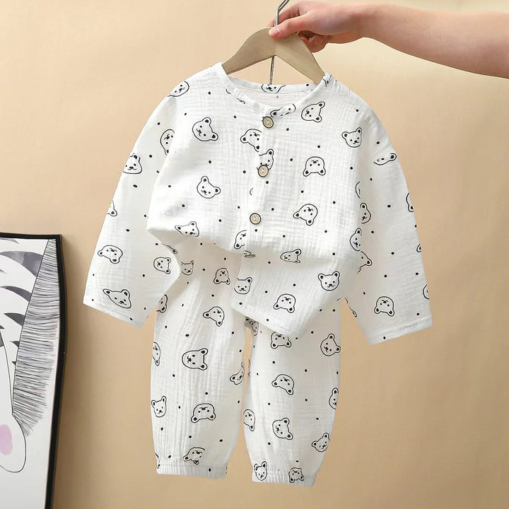 White baby cotton pajama set with black bear faces and dots, wooden buttons, held on hanger