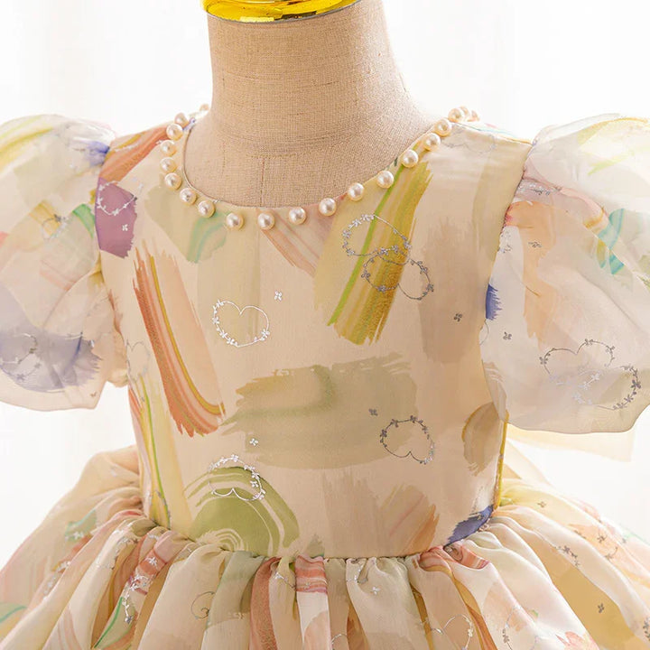Close-up of a pastel-colored toddler dress with puff sleeves, pearl neckline, and heart designs