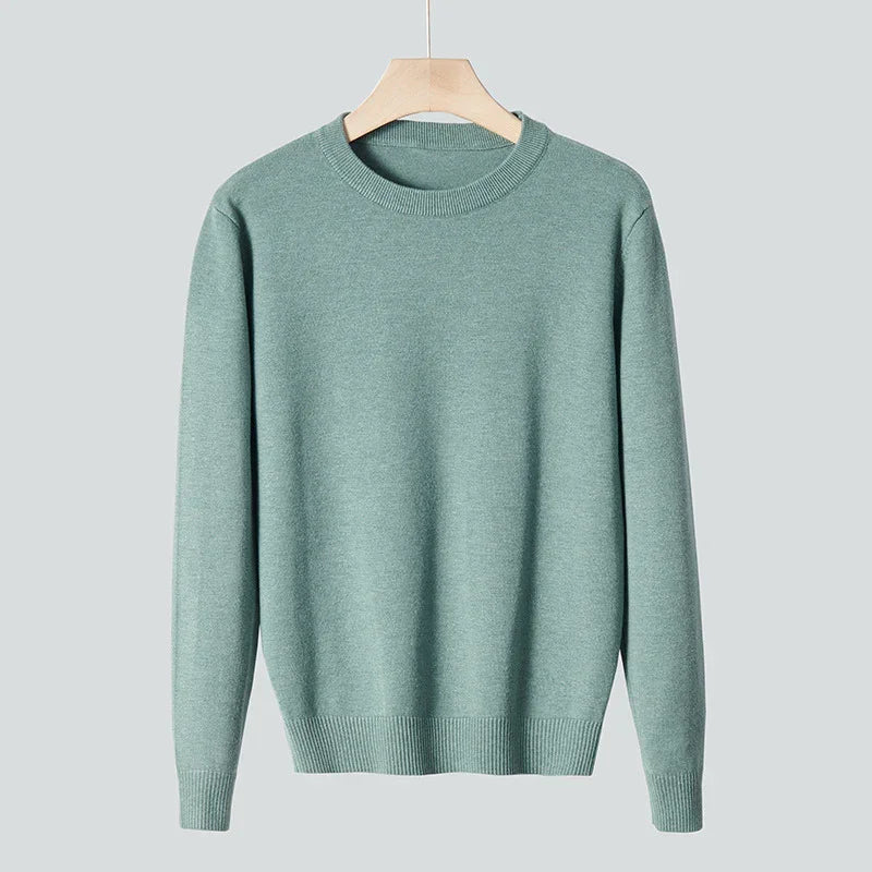 Soft green crew neck sweater hanging on wooden hanger against gray background