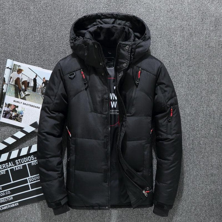 Black hooded puffer jacket with red zipper details laid on grey carpet with skateboard and film clapperboard