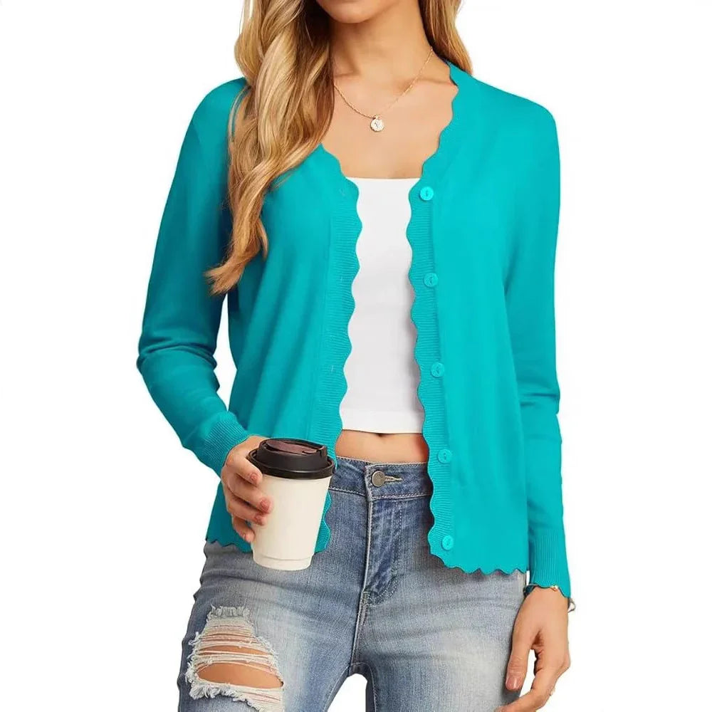 Woman in turquoise scalloped button-up cardigan, white crop top, ripped jeans holding coffee cup