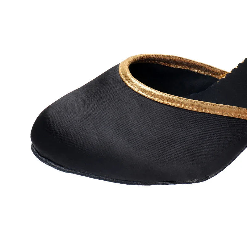 Black flat shoe with gold trim around the opening, close-up on the front part