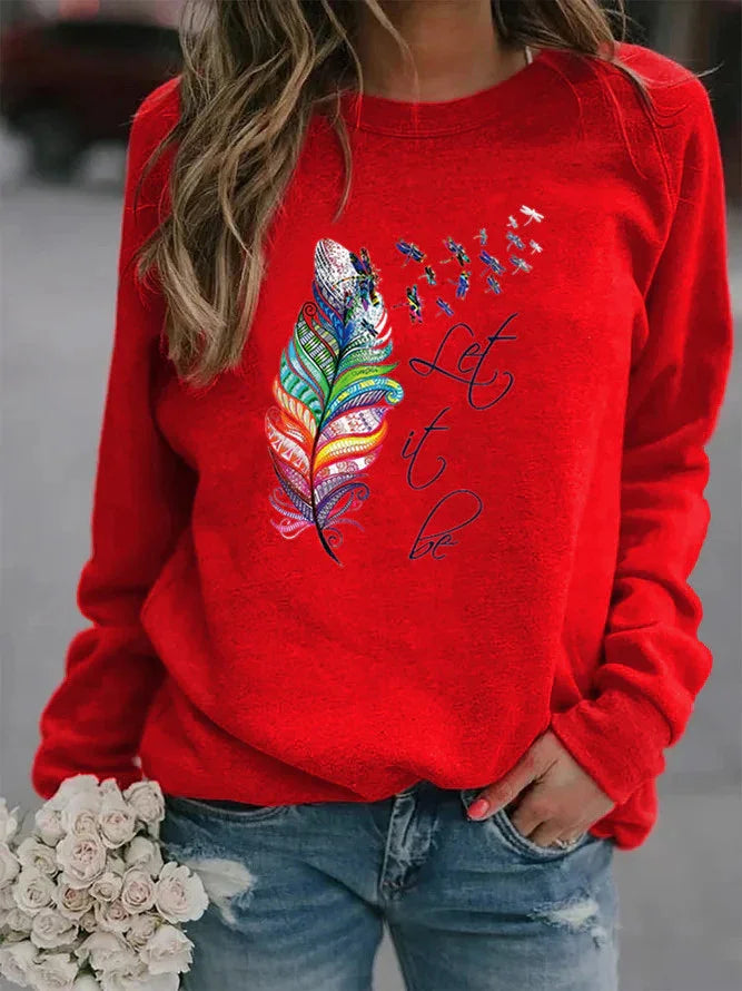 Woman wearing red sweatshirt with colorful feather and 'Let it be' text, holding white flowers