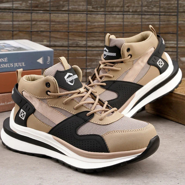 Beige and black athletic sneakers with mesh and synthetic material, placed on concrete with wooden background