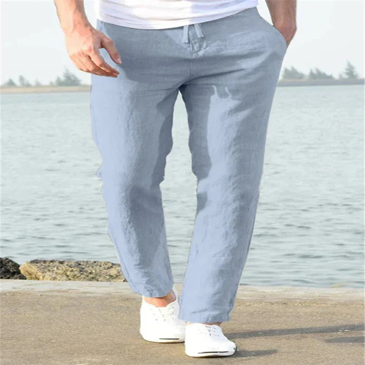 Man walking by the water wearing light blue casual pants and white sneakers