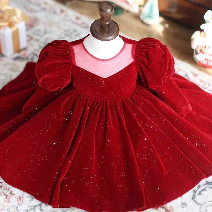 Elegant red velvet girl's dress with puff sleeves and sheer neckline on mannequin