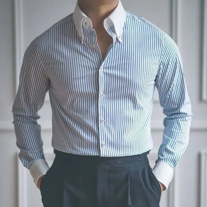 Man wearing a fitted blue striped dress shirt with white collar and cuffs, paired with black trousers