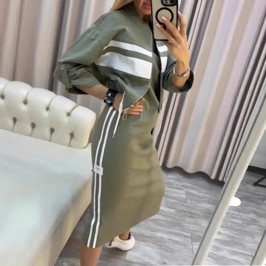 Woman in olive green sporty midi dress with white stripes taking a mirror selfie in a modern room