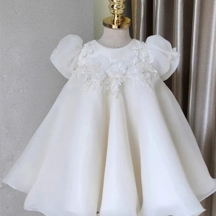 Elegant white baby dress with puff sleeves and floral lace applique on bodice