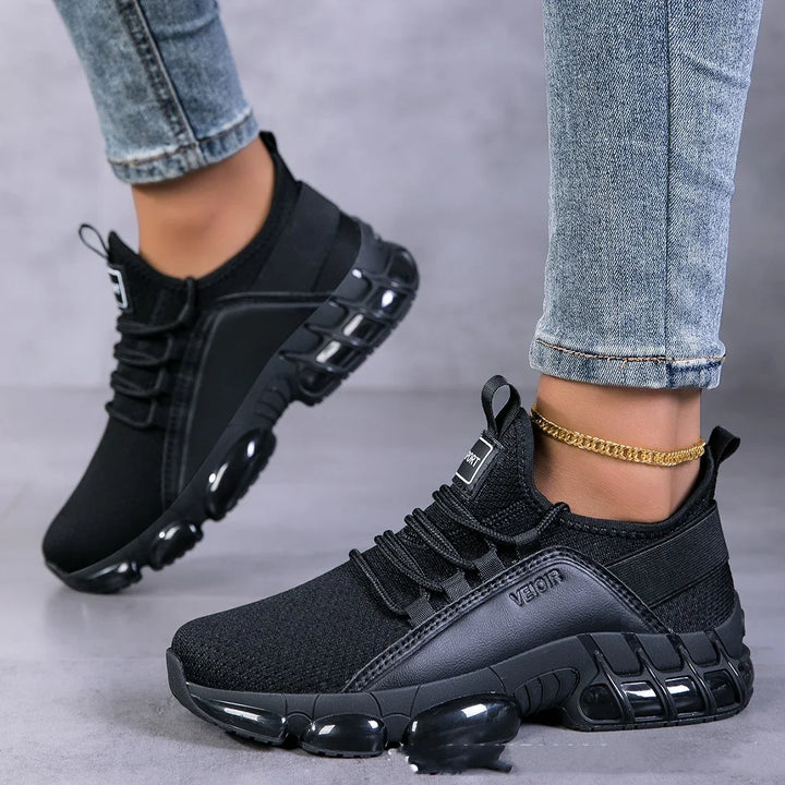 Black VEJOR sport sneakers with chunky sole worn with light blue jeans and gold anklet on gray floor