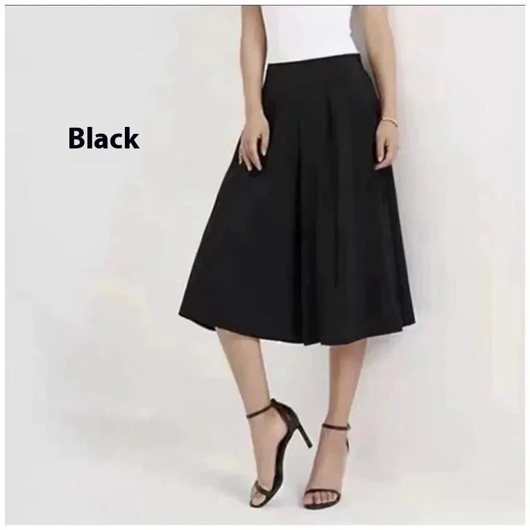 Woman wearing black midi skirt and black ankle-strap high heels against white background