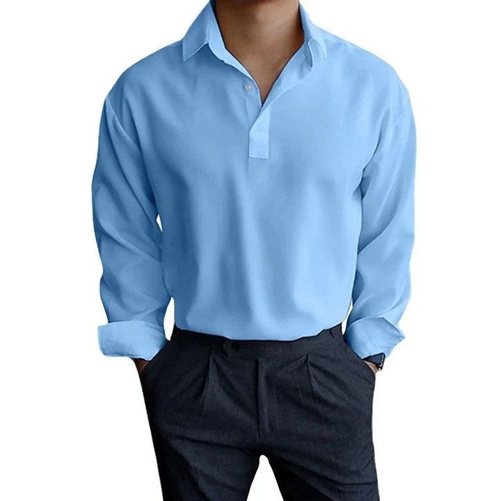 Man wearing light blue long-sleeve casual shirt with black pleated pants, hands in pockets