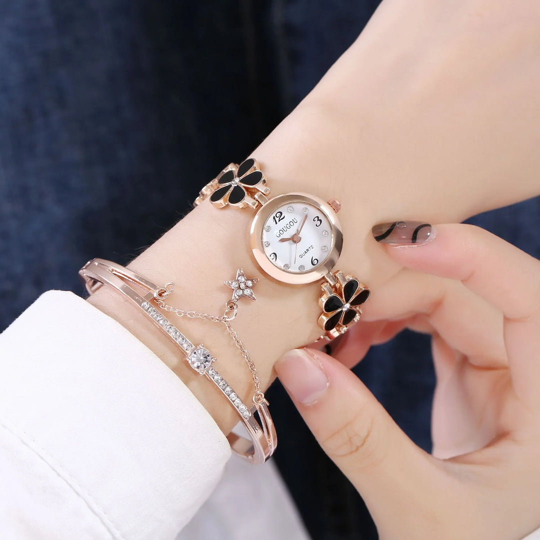 Rose gold wristwatch with black flower accents and pearl dial paired with rhinestone bracelet