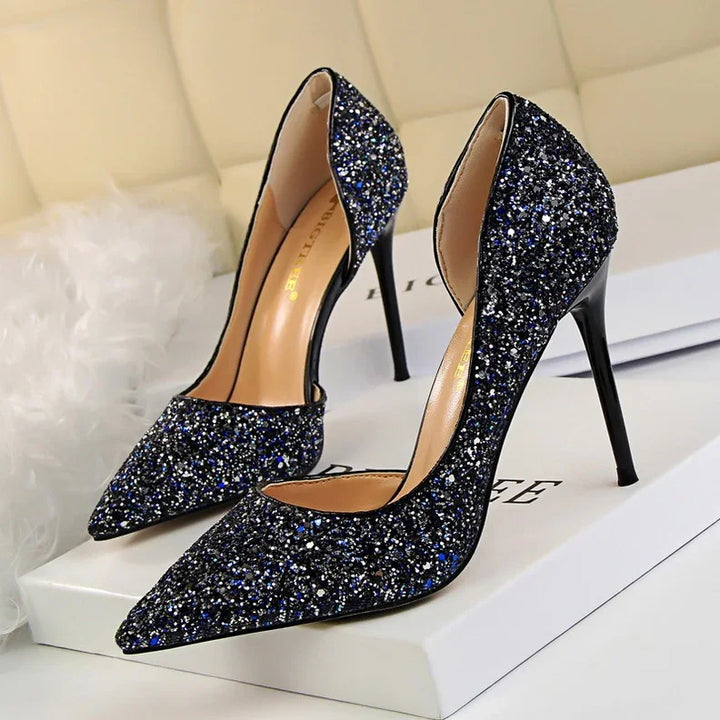 Pair of black glitter stiletto high heels with pointed toes on a white box