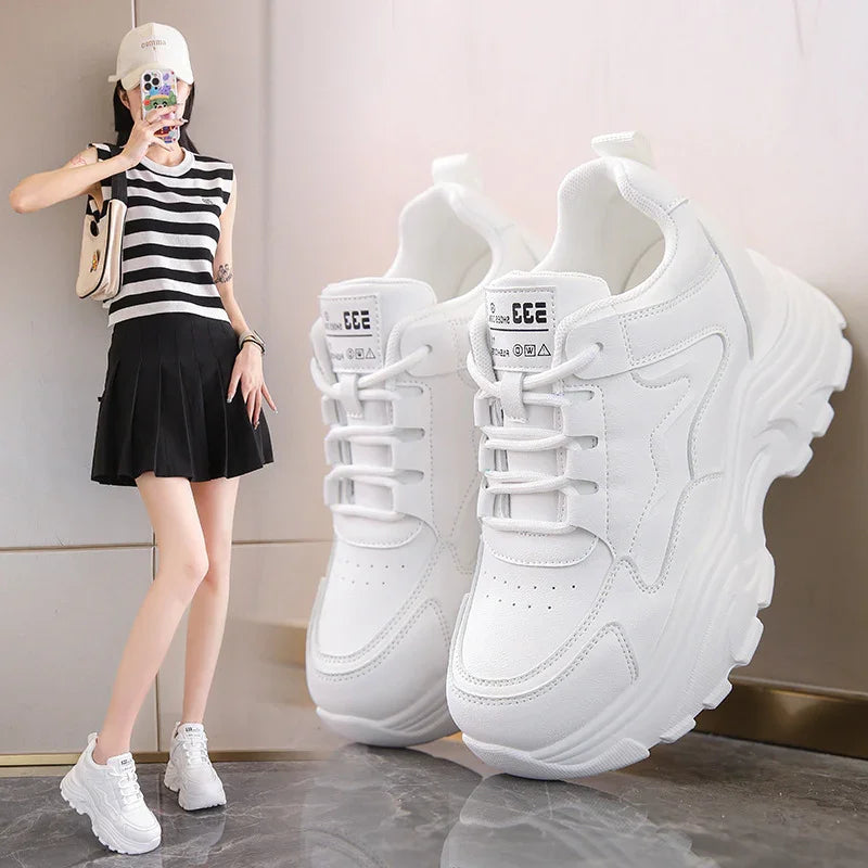 White chunky platform sneakers with star design worn by woman in black skirt and striped top