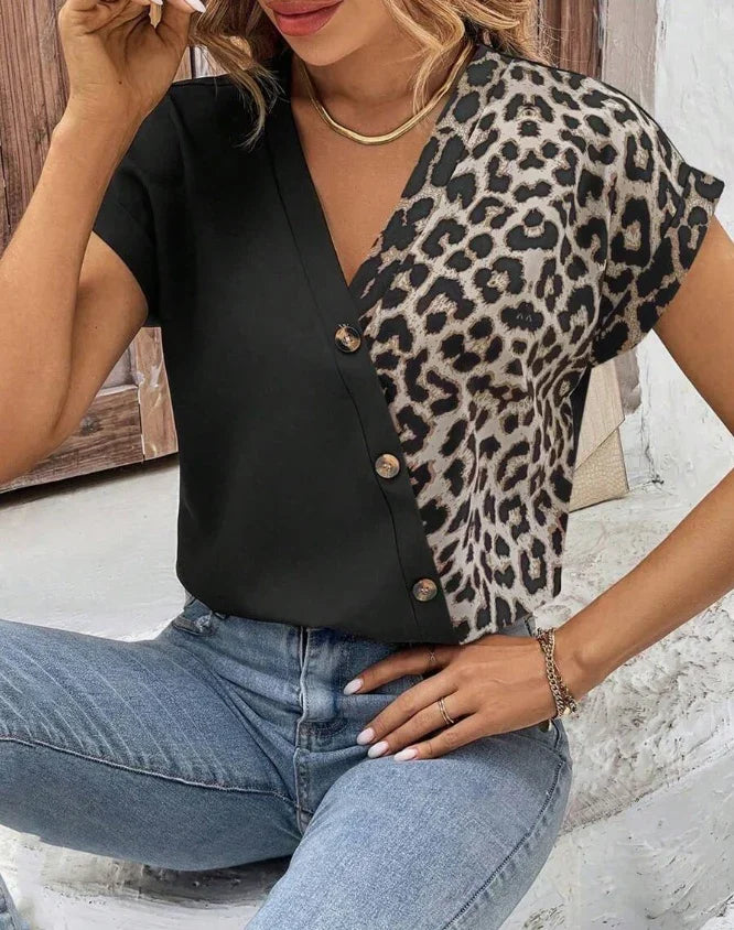 Woman wearing black and leopard print buttoned V-neck top with short sleeves and light blue jeans