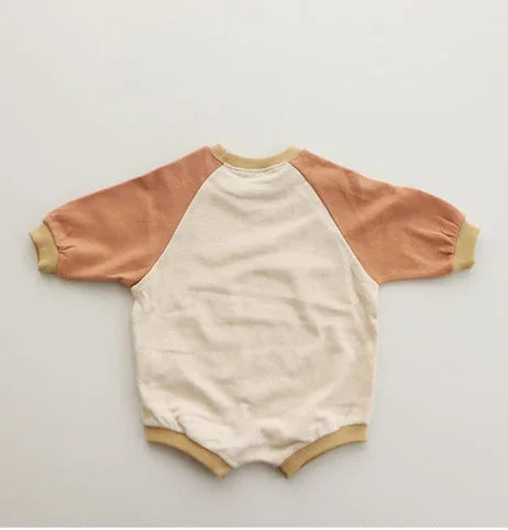baby romper with cream body and light brown raglan sleeves on beige background