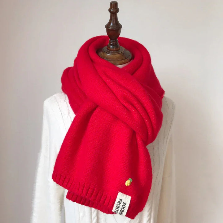 Bright red knitted scarf with pineapple emblem on white mannequin bust