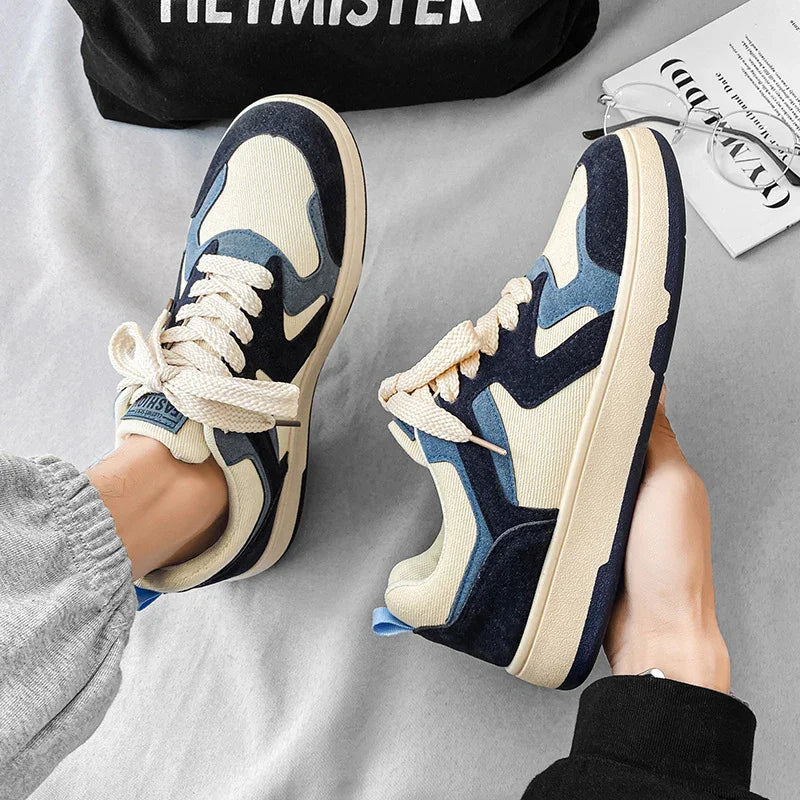 Casual blue and beige sneakers with thick cream laces worn indoors on light gray fabric surface