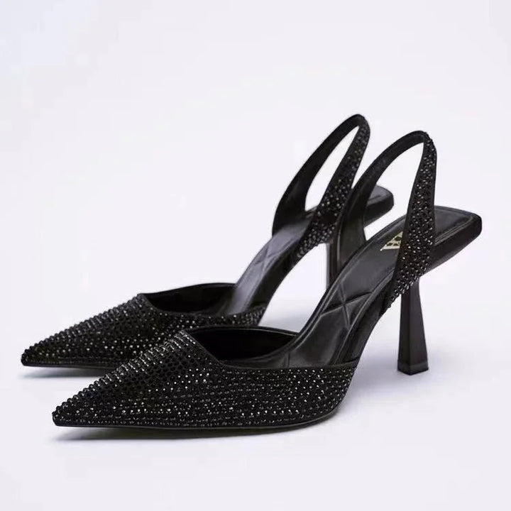 Elegant black pointed-toe slingback heels with sparkling rhinestone embellishments on white background