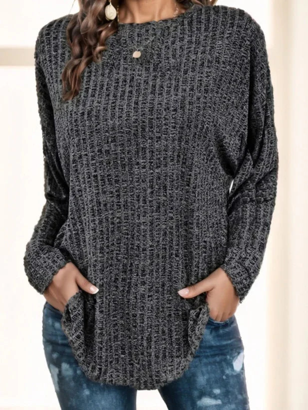 Woman wearing dark gray waffle knit long sleeve sweater with pockets and blue distressed jeans