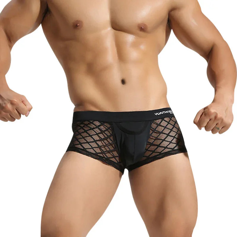 Fit male model wearing black mesh boxer briefs with a geometric pattern on a white background