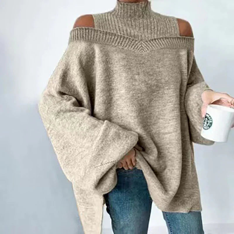 Beige cold shoulder oversized knit sweater with turtleneck worn with blue jeans, holding a white mug