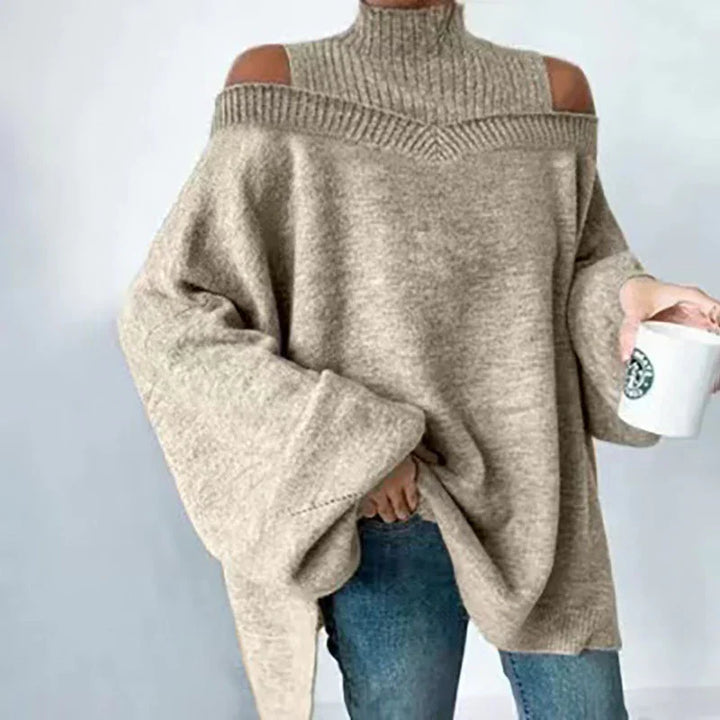 Beige cold shoulder oversized knit sweater with turtleneck worn with blue jeans, holding a white mug