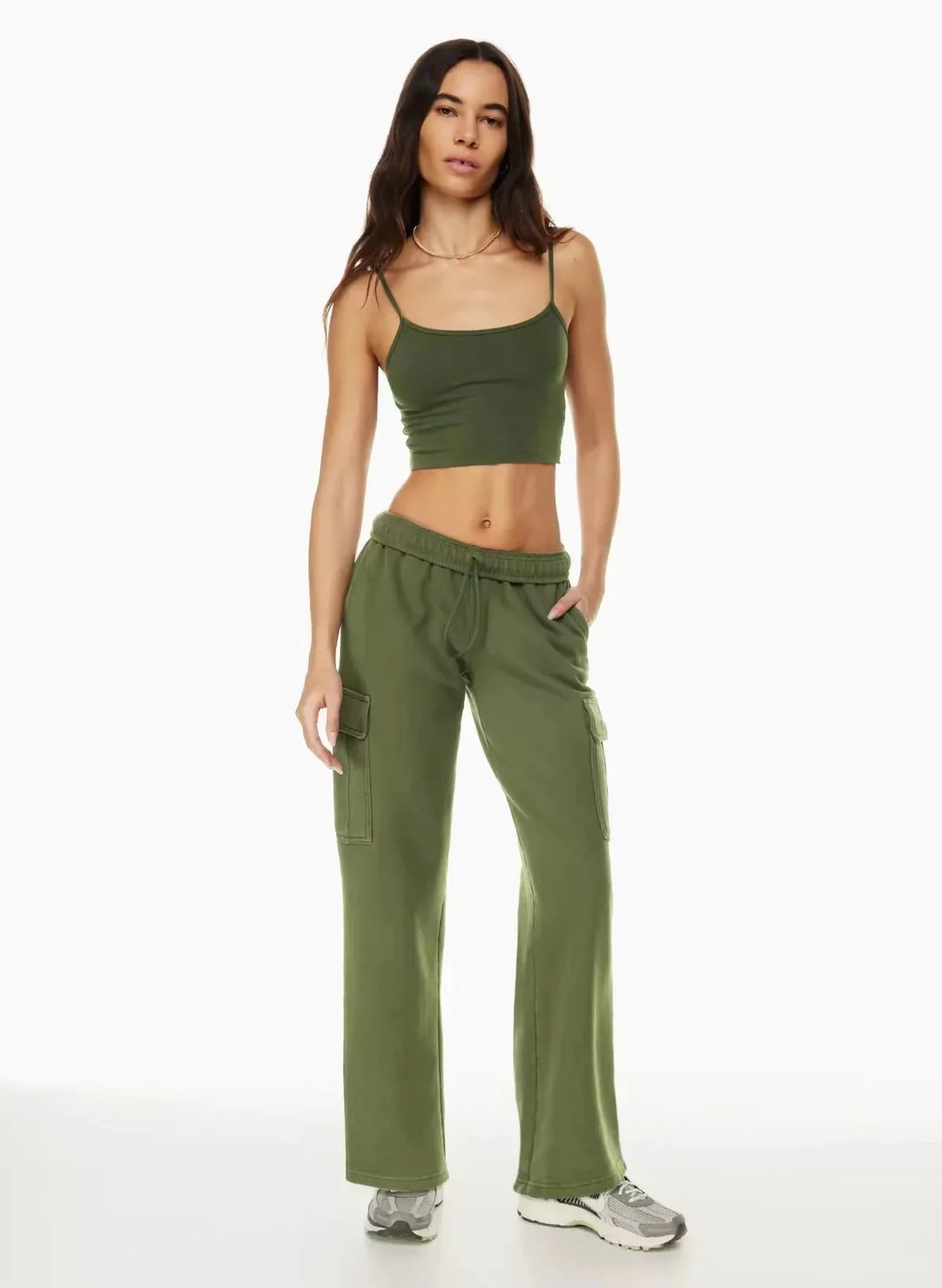 Woman wearing olive green crop top and cargo pants with sneakers on white background