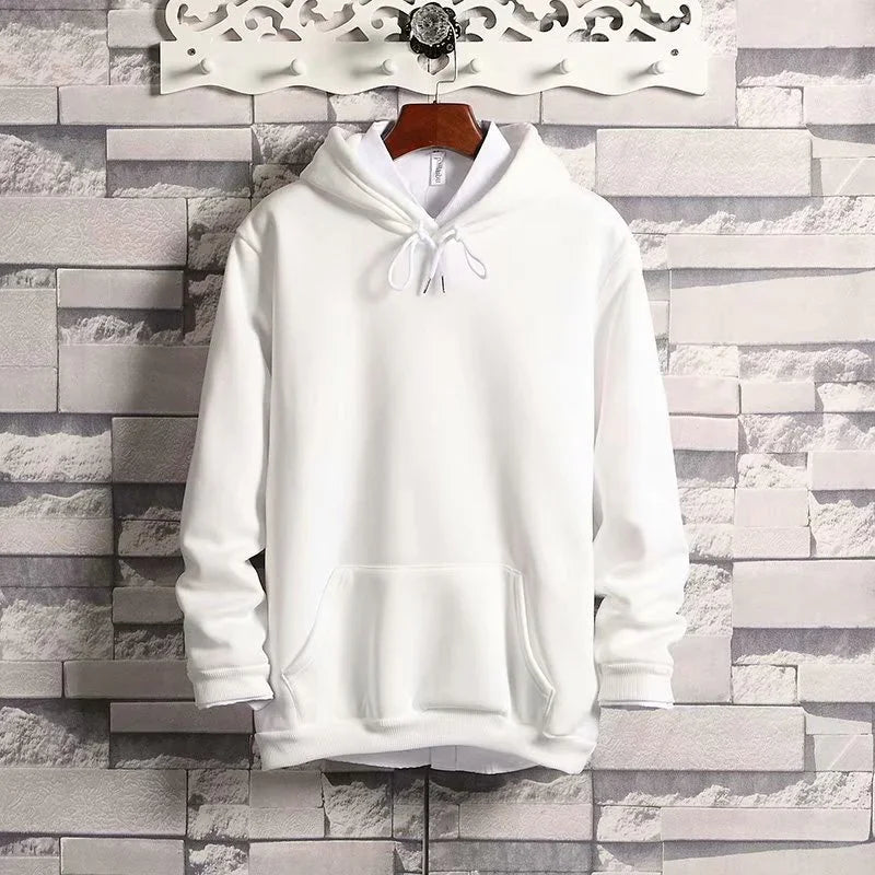Plain white hoodie with front pocket and drawstring hood hanging on wooden hanger against textured brick wall