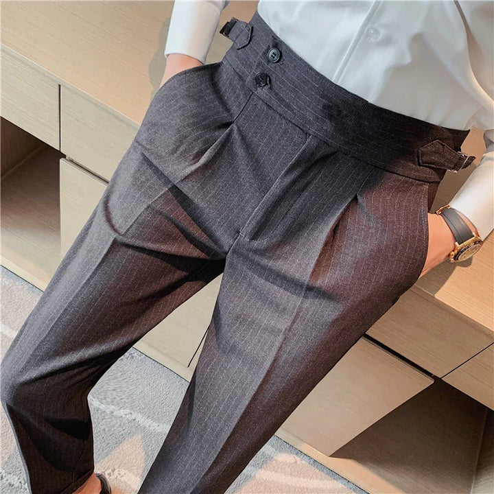 Close-up of high-waisted dark gray pinstripe dress pants with double buttons and side adjusters, worn with white shirt and watch
