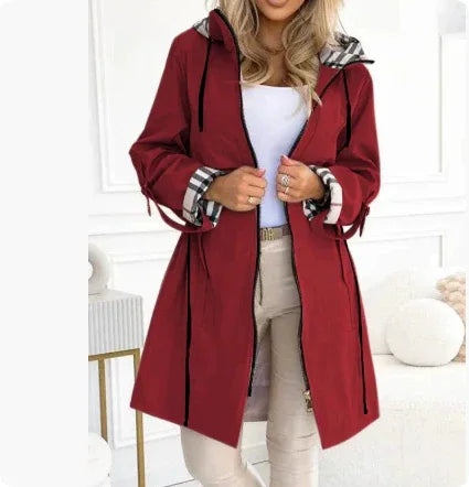 Woman wearing stylish red hooded coat with plaid cuffs and beige pants indoors