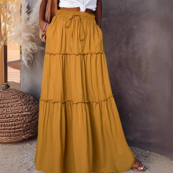Woman wearing mustard yellow tiered maxi skirt with drawstring waist and pockets