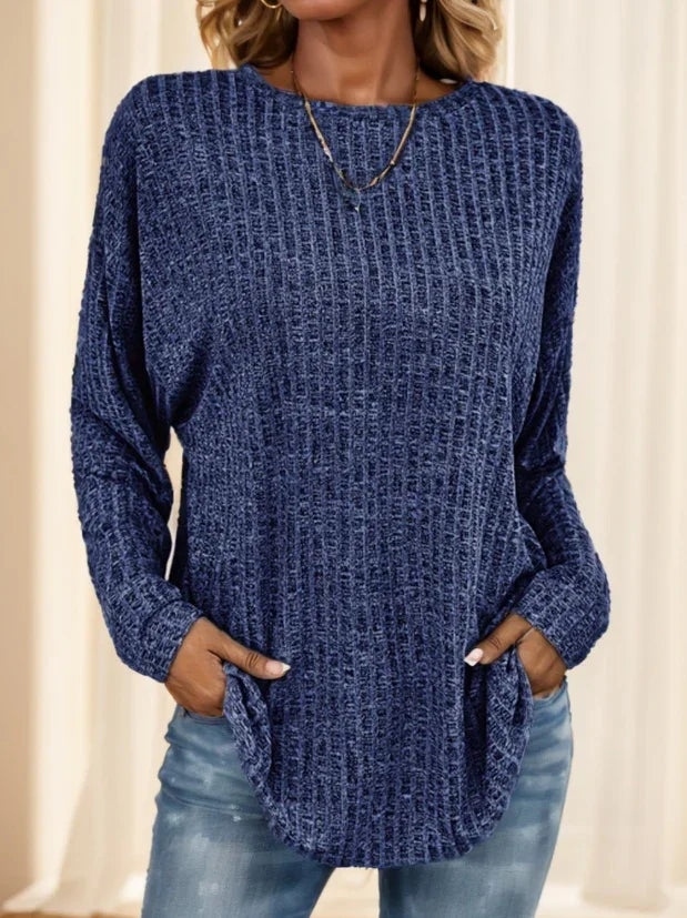 Woman wearing a textured navy blue long sleeve sweater with pockets and light blue jeans
