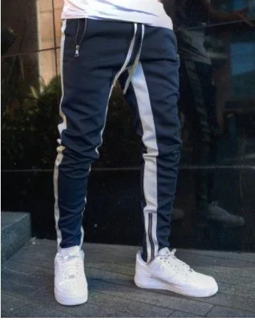Man wearing navy jogger pants with white stripes and white sneakers outdoors