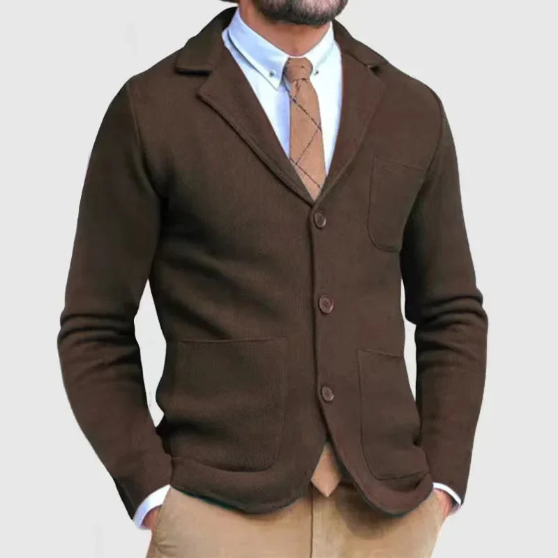 Man wearing a brown button-up cardigan over a light blue shirt and brown tie, paired with beige pants