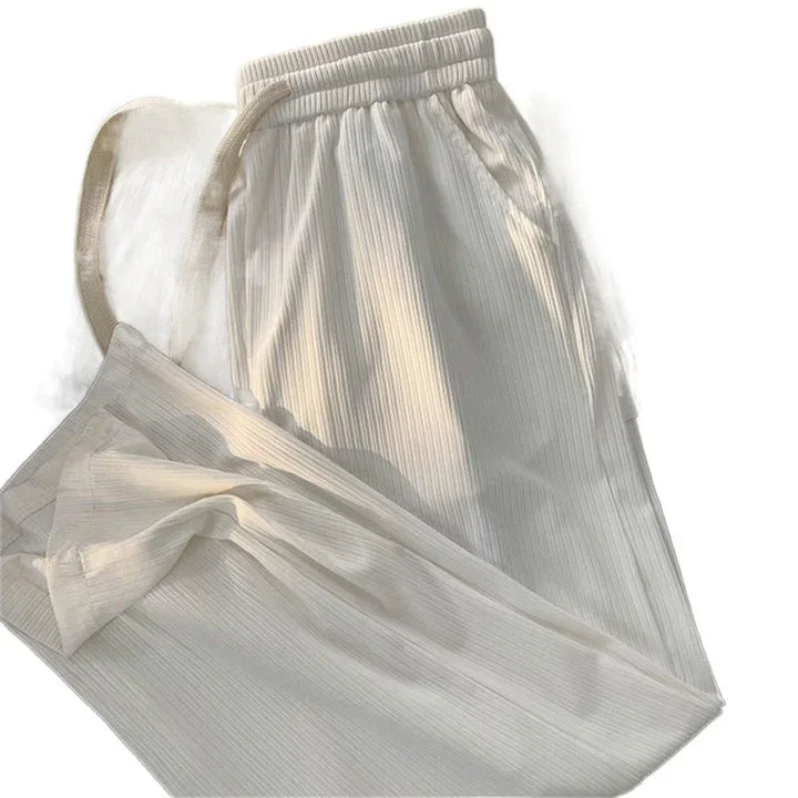 Cream ribbed knit lounge pants with elastic waistband and side pockets on white background