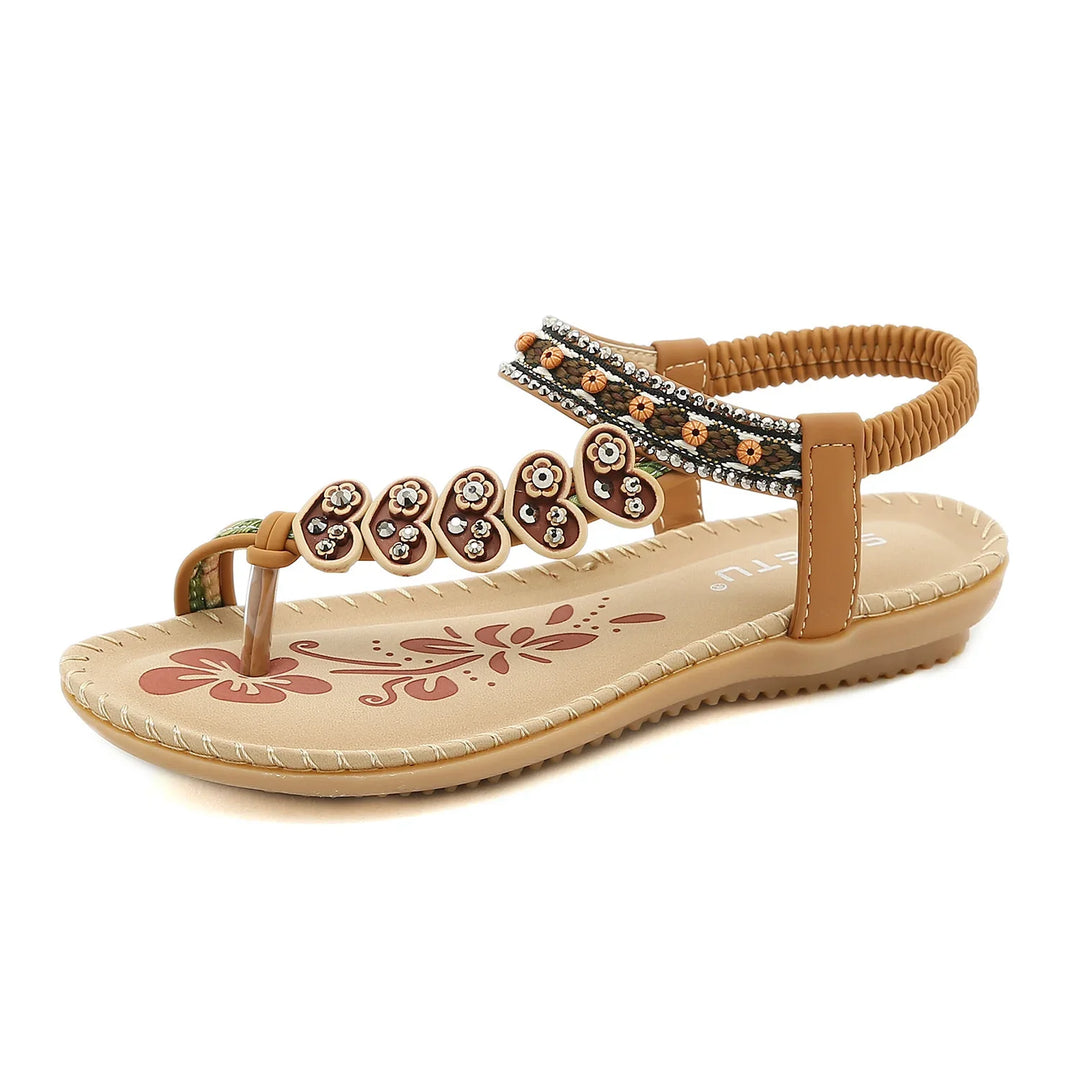 Brown women's sandal with floral decorations and beaded ankle strap on beige sole