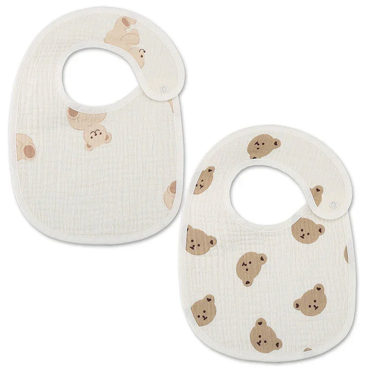 Two white baby bibs with beige teddy bear faces pattern, soft cotton fabric, snap closures