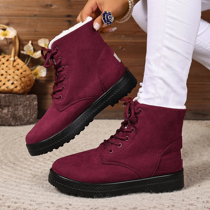 Women's burgundy winter boots with black soles and white fleece lining worn with white pants