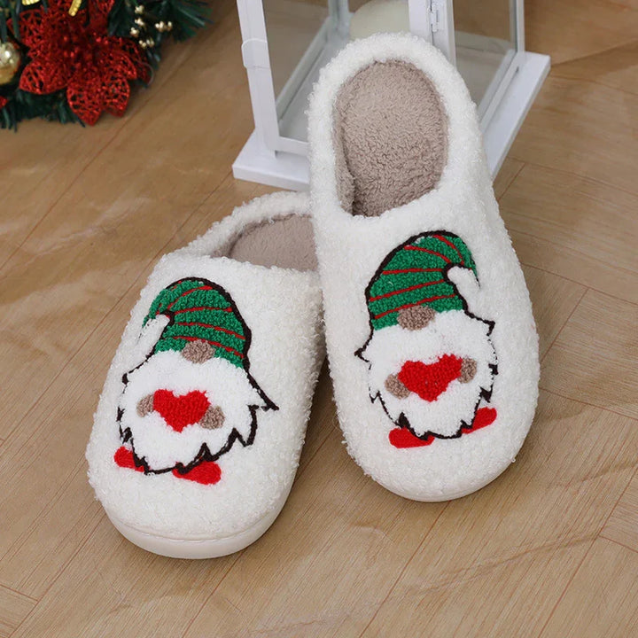Cozy white Christmas slippers with gnome embroidery wearing a green hat and holding a red heart on wooden floor