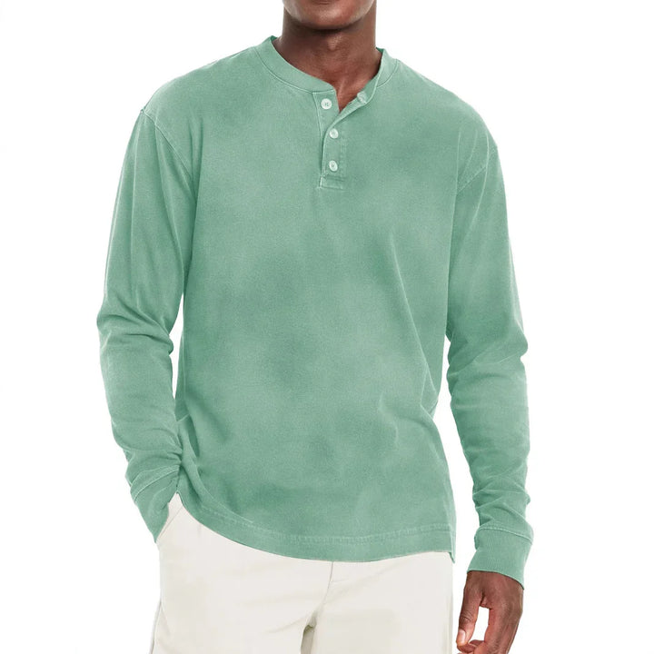Man wearing a sage green long-sleeve henley shirt with three buttons and cream pants