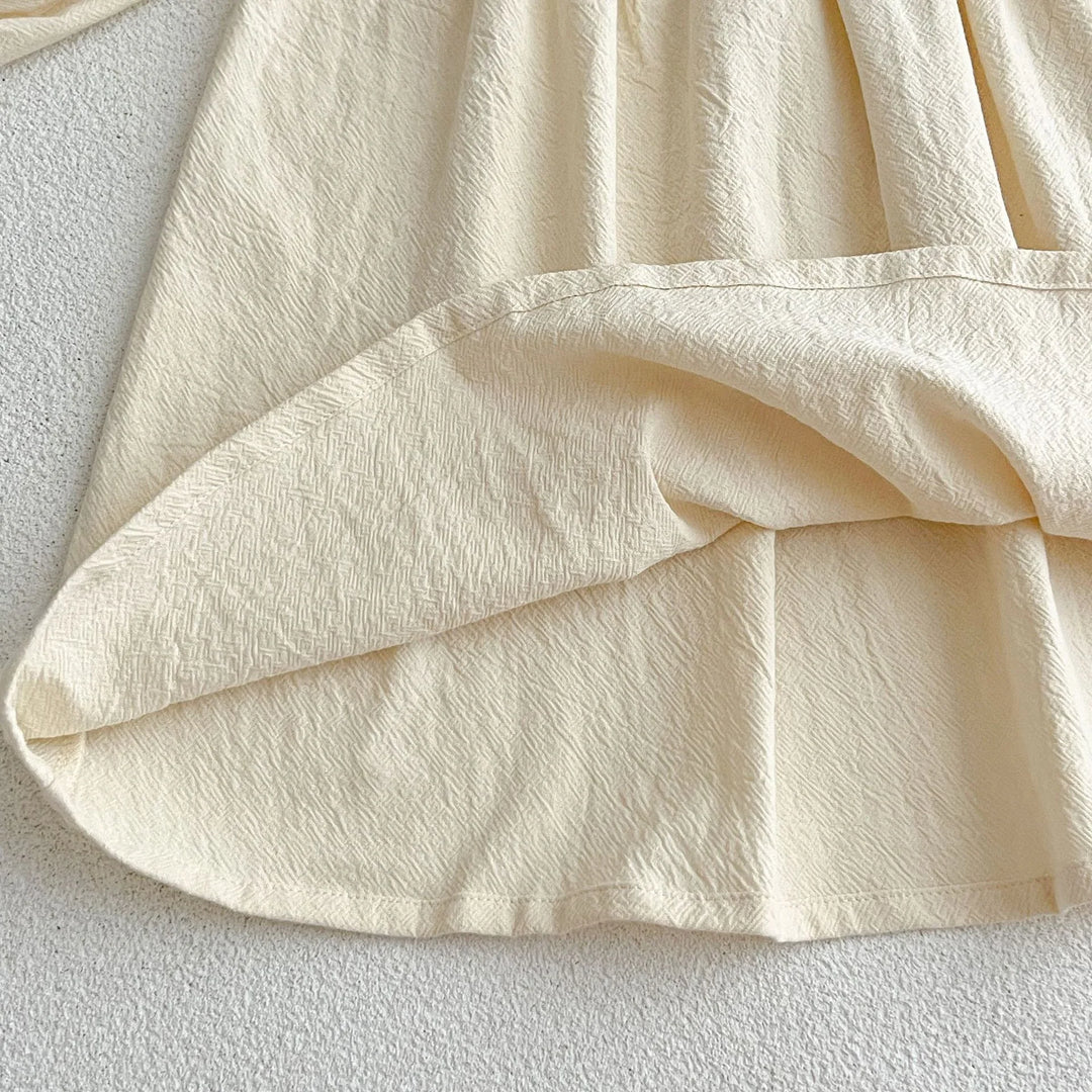 Close-up of cream textured fabric with stitched hem on a light surface