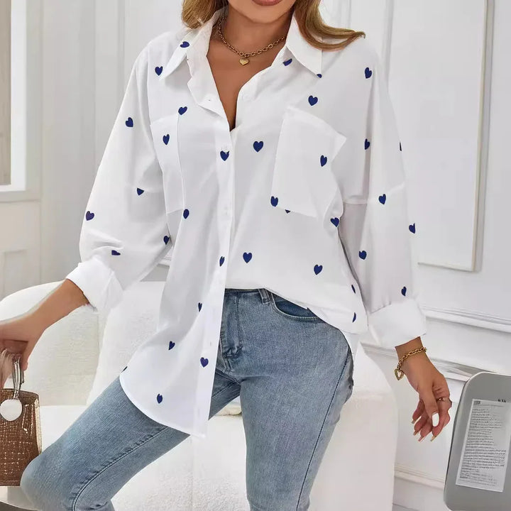 Woman wearing white button-up shirt with blue heart prints and light blue jeans in modern room