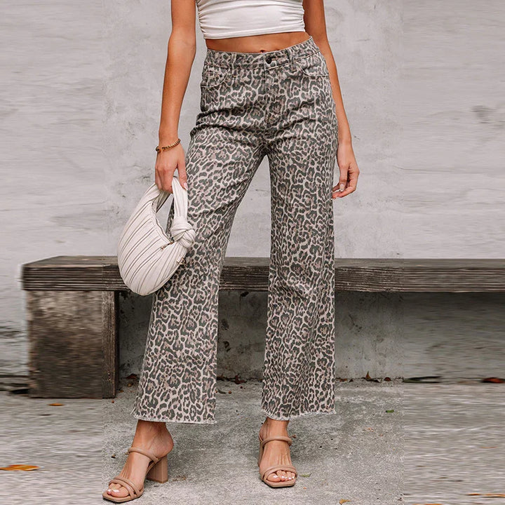 Woman wearing leopard print high-waist wide leg pants with nude block heel sandals and holding a white knot bag